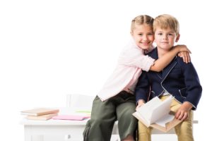 adorable happy schoolkids hugging while studying together isolated on white